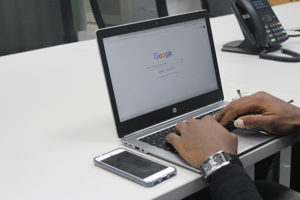 Person typing on laptop showing Google search homepage