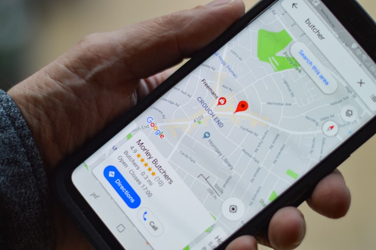 Hand holding smartphone showing Google Maps business listing with star ratings